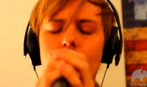 A young man singing live into a microphone.