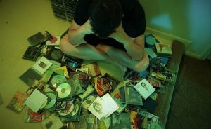 A man sitting on the floor in front of a pile of CDs