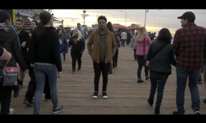 A group of people walking on a pier at sunset.