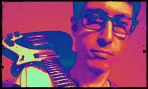 A man with glasses, Steve Ostrov, holding a guitar.