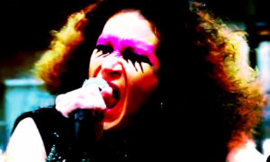 A woman with long curly hair passionately singing