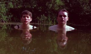 A man and woman standing in a body of water.